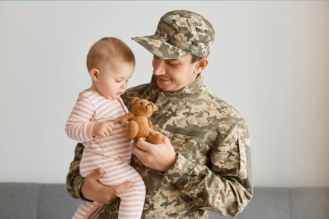 Military member giving a bear to his daughter