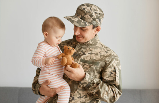 Military member giving a bear to his daughter