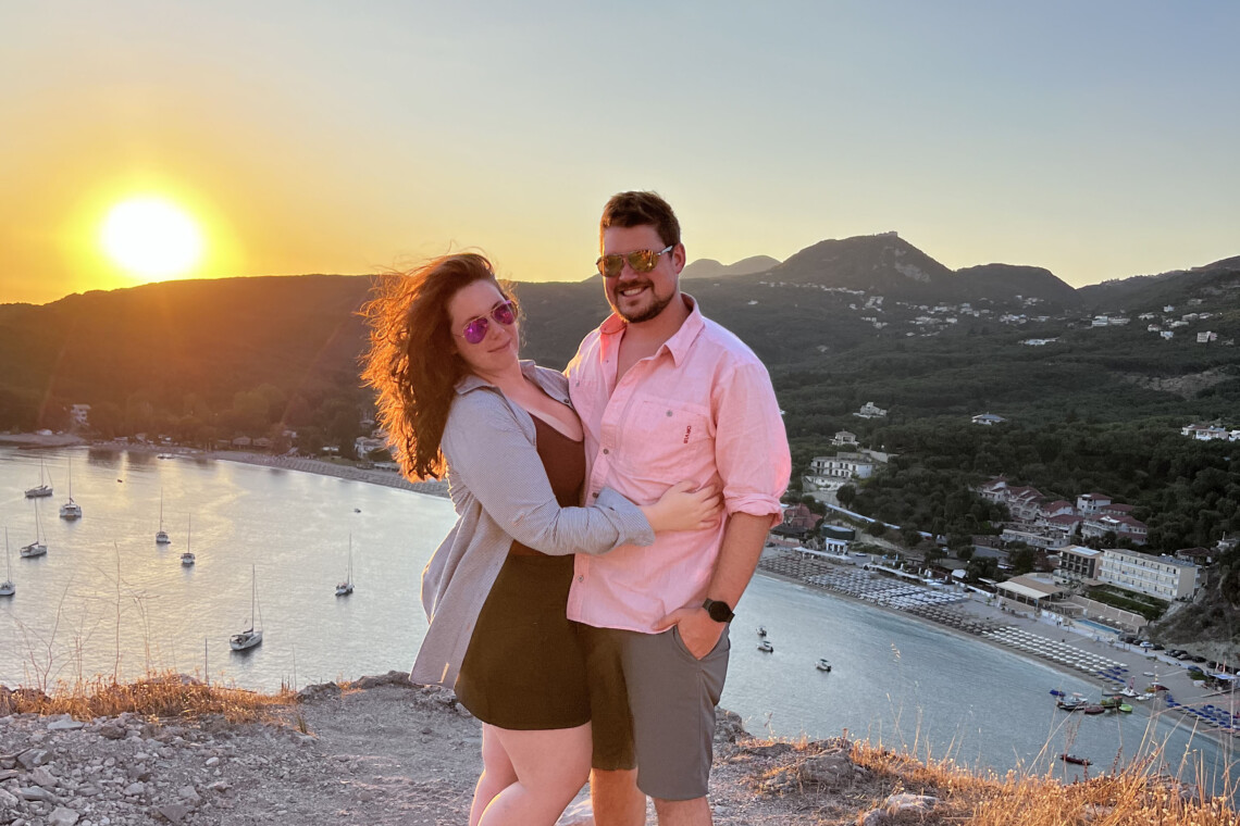 A couple (Brittany and Daniel) stand in front of a sunset.